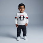 Niño pequeño con suéter blanco tejido de Mickey Mouse y pantalón de mezclilla oscuro de la marca EmpiBy