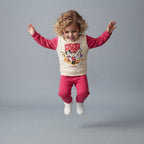 Niña saltando con conjunto EmpiBy de dos piezas, sudadera crema y pantalón fucsia con estampado de Mickey & Friends