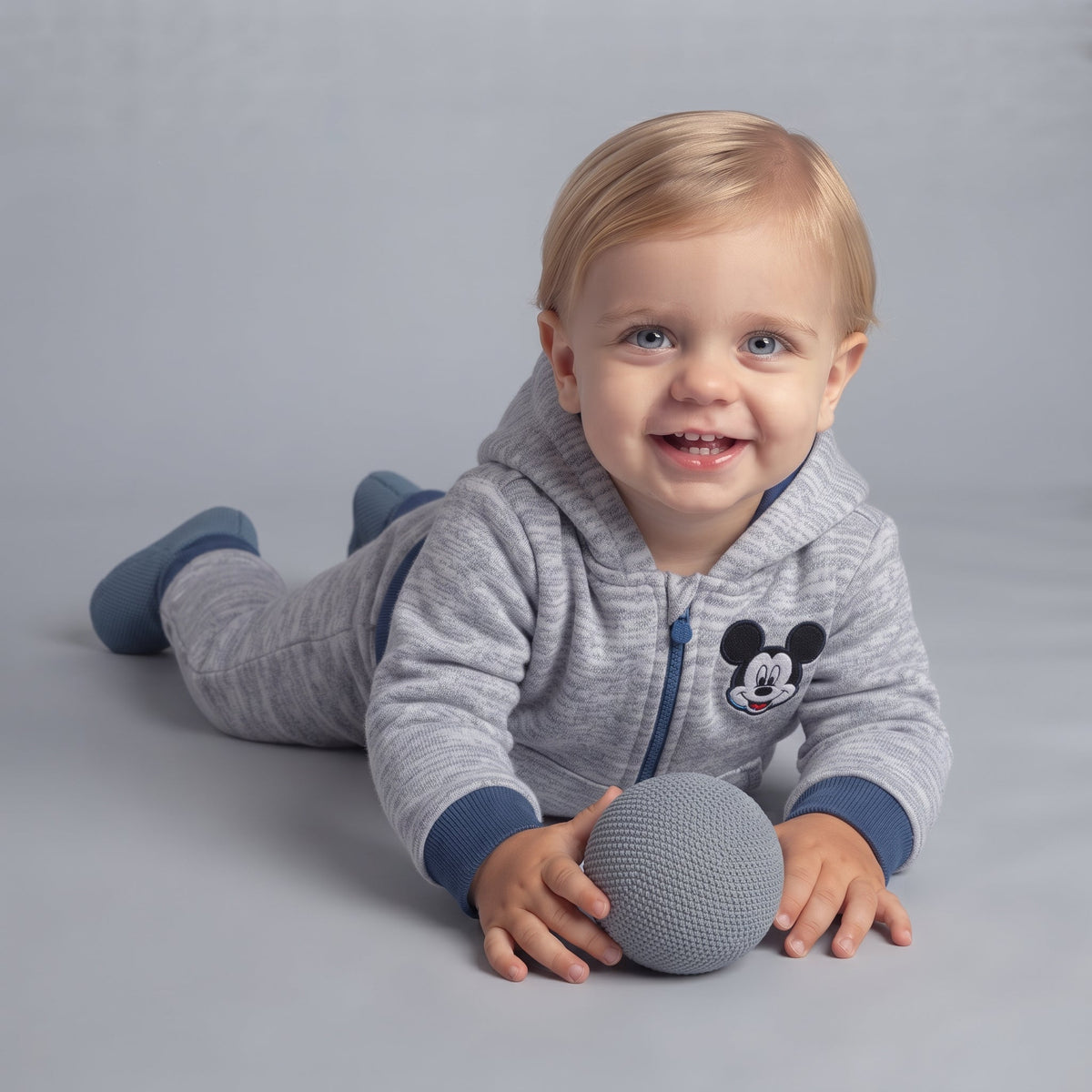 Bebé sonriente con sudadera EmpiBy gris de Mickey Mouse con capucha y cierre, conjunto cómodo de dos piezas