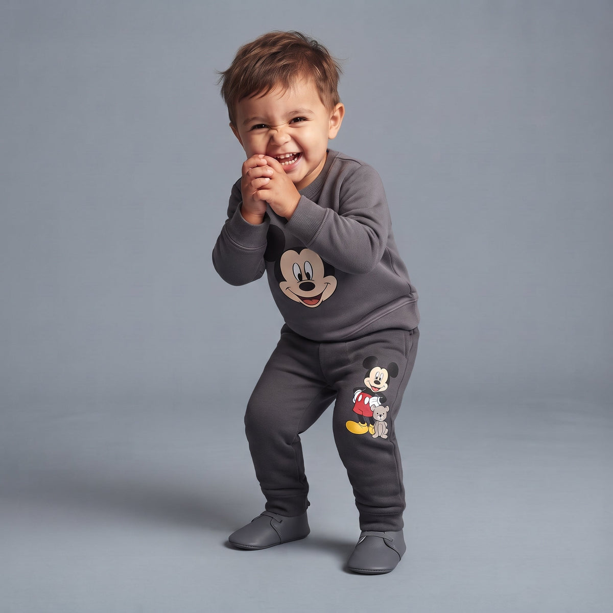Niño feliz vistiendo conjunto EmpiBy de dos piezas gris con estampado de Mickey Mouse y pantalón tipo jogger cómodo.