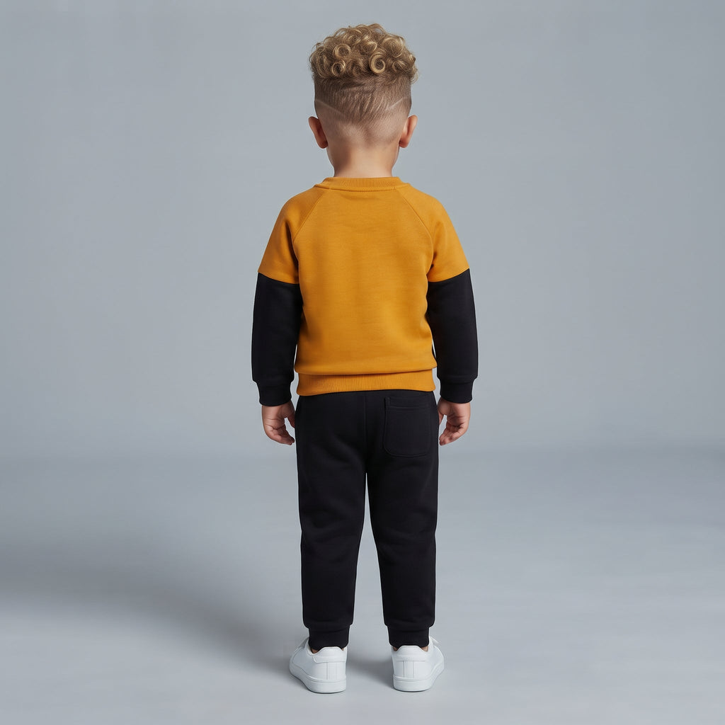Vista trasera de niño con conjunto EmpiBy de sudadera mostaza y negra y pantalón jogger negro a juego