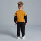 Vista trasera de niño con conjunto EmpiBy de sudadera mostaza y negra y pantalón jogger negro a juego