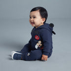 Bebé sonriente vistiendo conjunto EmpiBy de dos piezas azul marino con capucha de orejas de Mickey Mouse y joggers.