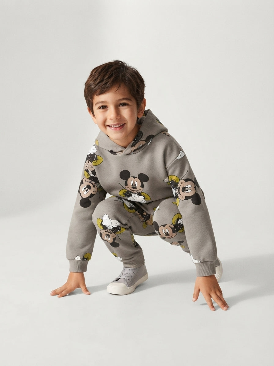 Niño sonriente con conjunto EmpiBy de sudadera y jogger color café con estampado de Mickey Mouse en tonos tierra