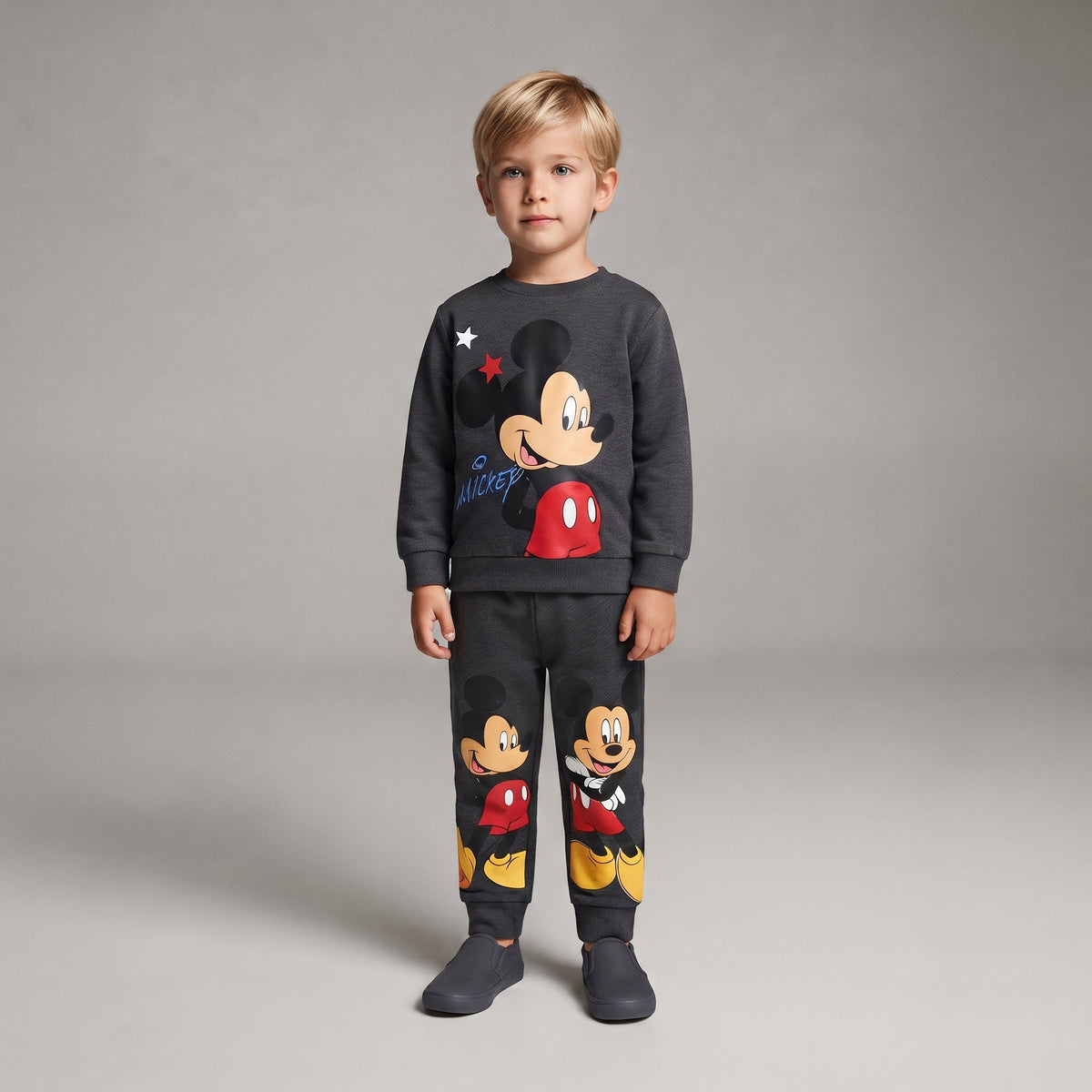 Niño vistiendo conjunto EmpiBy de dos piezas gris con estampado de Mickey Mouse, sudadera y pantalón jogger a juego.