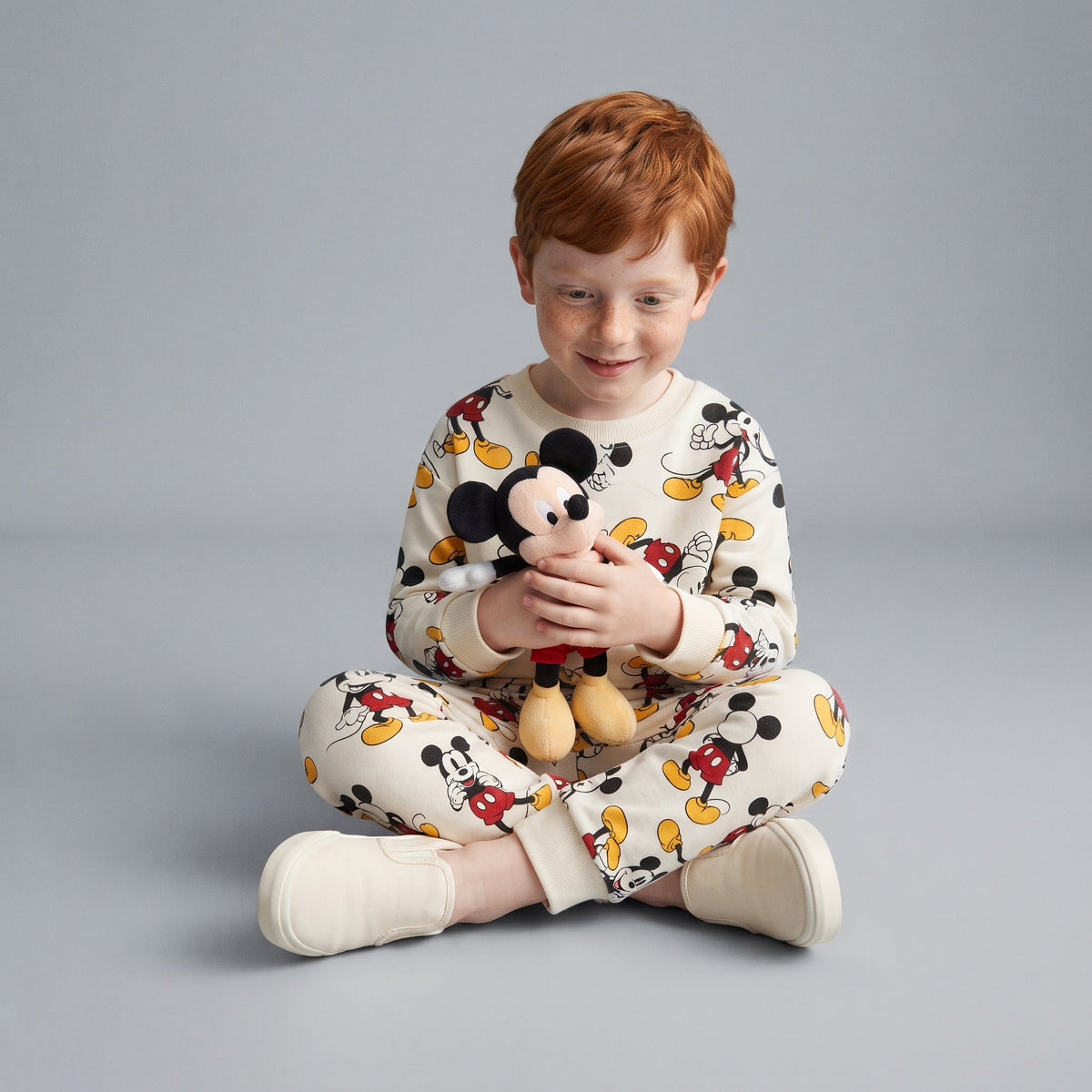 Niño sentado con conjunto de dos piezas EmpiBy color marfil con estampado de Mickey Mouse y felpa suave