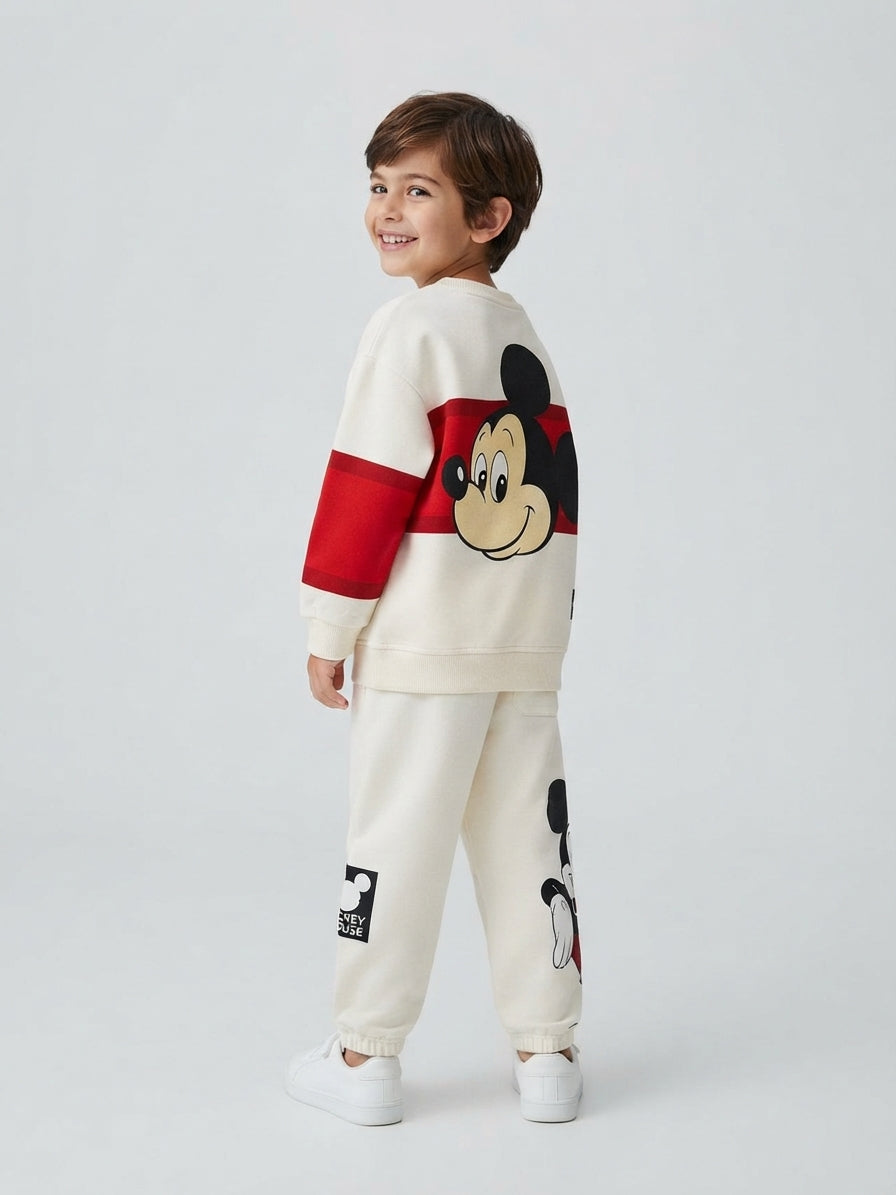 Niño sonriente vistiendo conjunto EmpiBy de sudadera y pantalón Mickey Mouse en tonos marfil y rojo