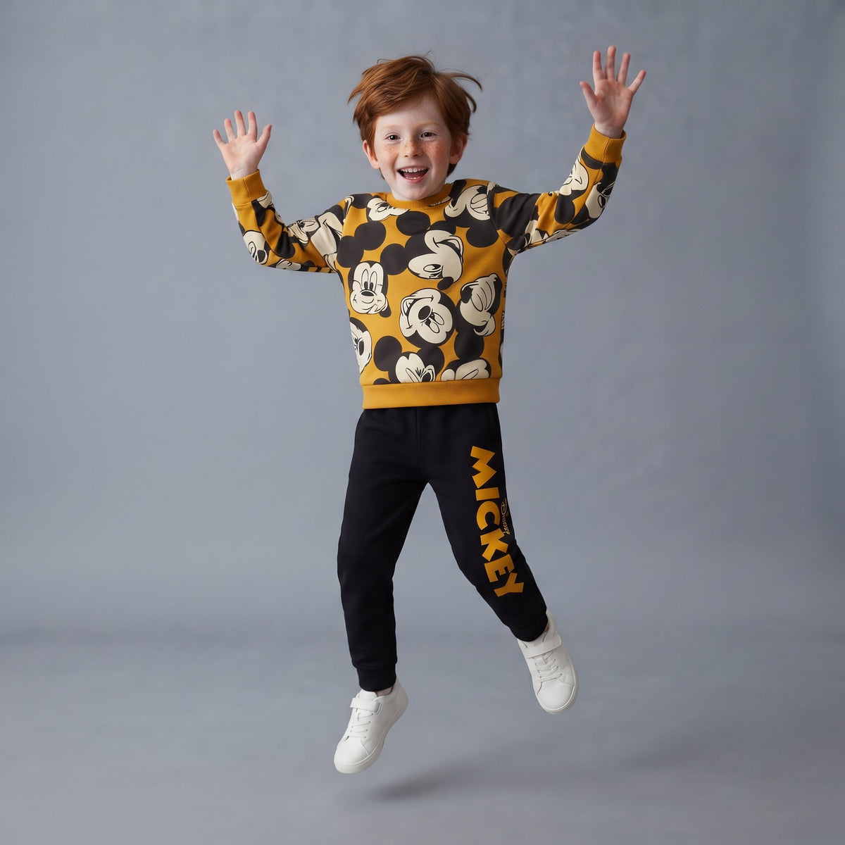 Niño saltando con conjunto EmpiBy de dos piezas de Mickey Mouse, sudadera estampada y pantalón jogger negro