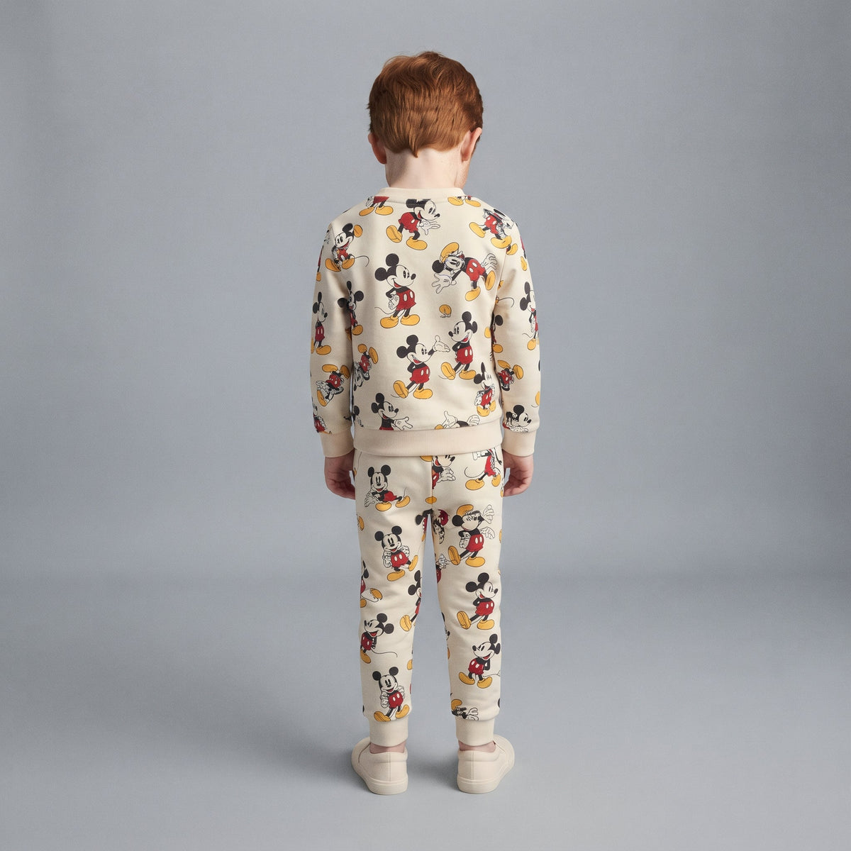 Conjunto de dos piezas EmpiBy para niño en color marfil con estampado integral de Mickey Mouse y diseño de felpa.
