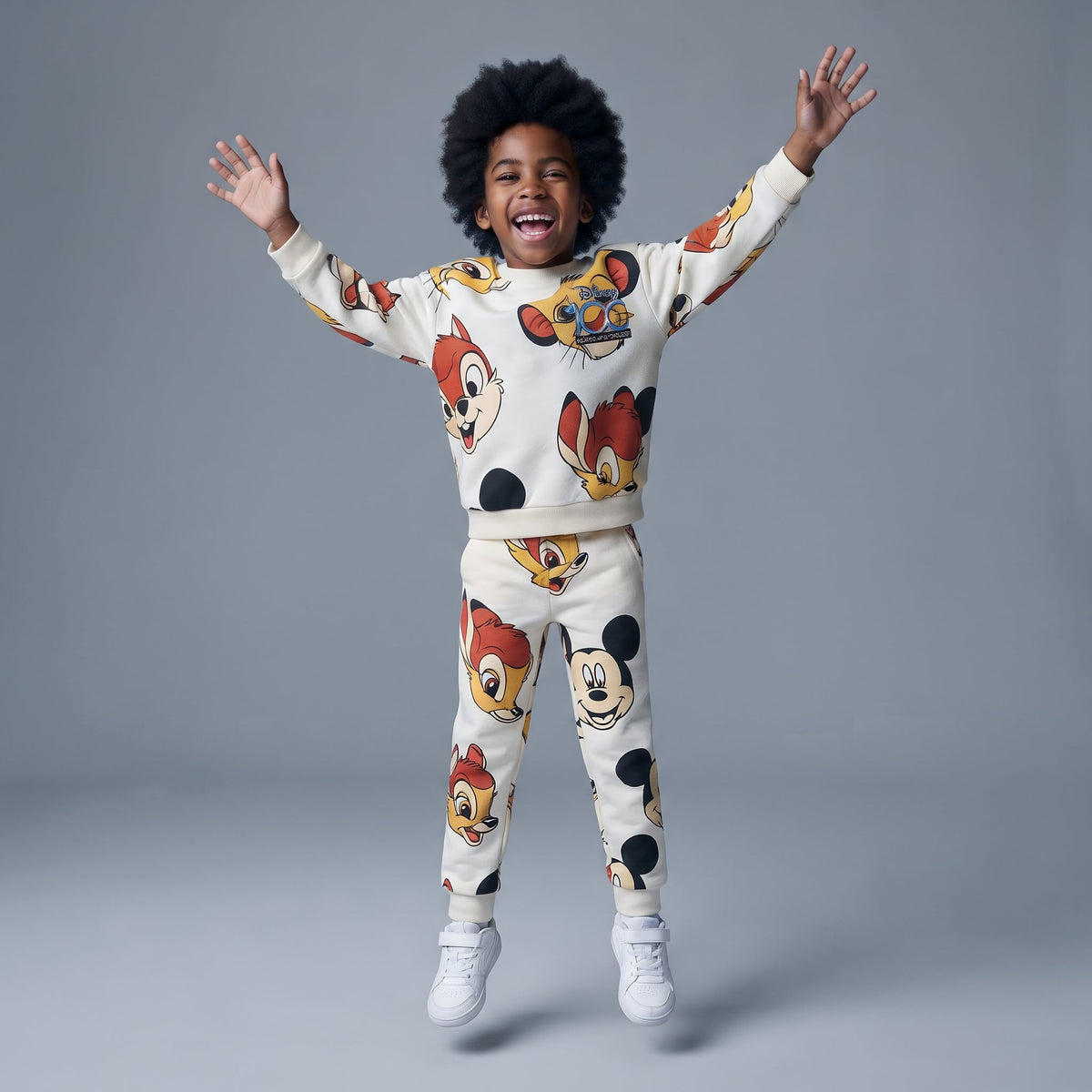 Niño saltando feliz con conjunto de sudadera y jogger EmpiBy de color crema con estampado de Mickey Mouse y amigos