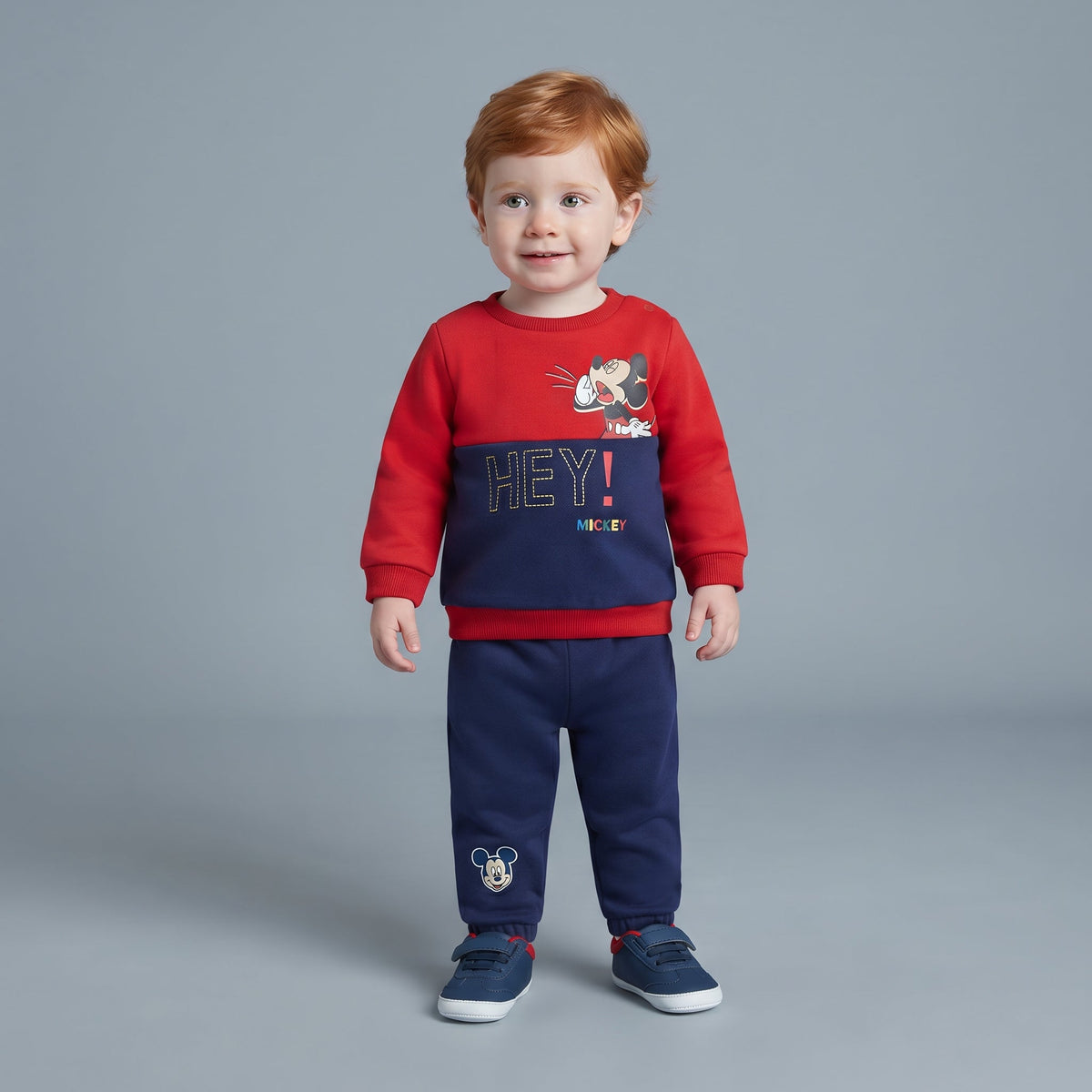 Niño pequeño vistiendo conjunto EmpiBy de dos piezas con sudadera roja y azul de Mickey Mouse y pantalón jogger