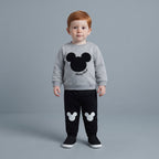 Niño pequeño vistiendo conjunto EmpiBy de sudadera gris con Mickey Mouse y pantalón jogger negro con siluetas