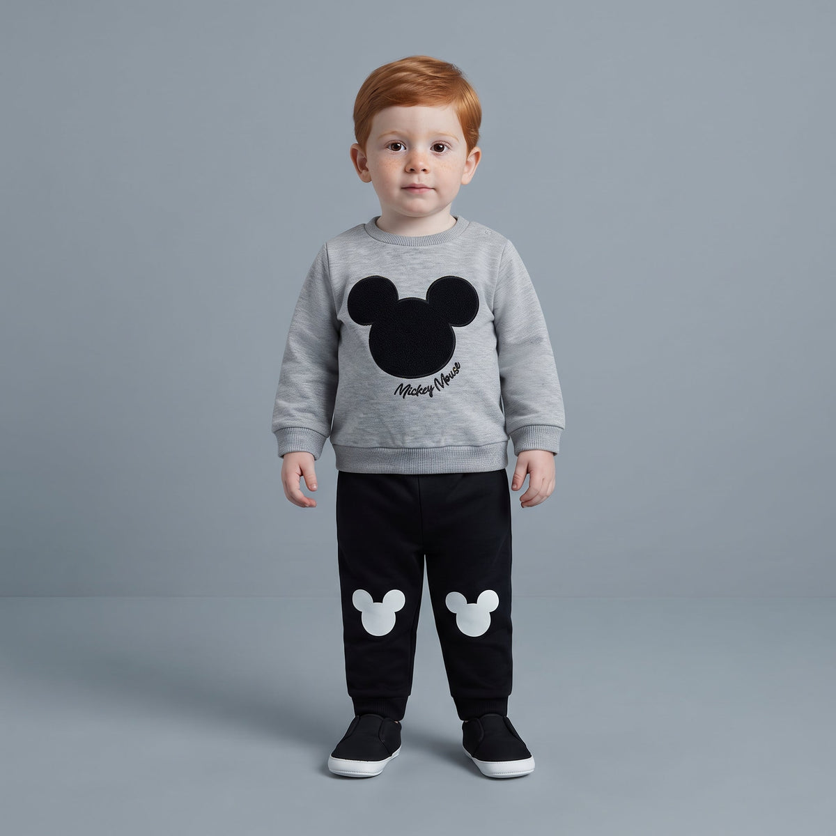 Niño pequeño vistiendo conjunto EmpiBy de sudadera gris con Mickey Mouse y pantalón jogger negro con siluetas