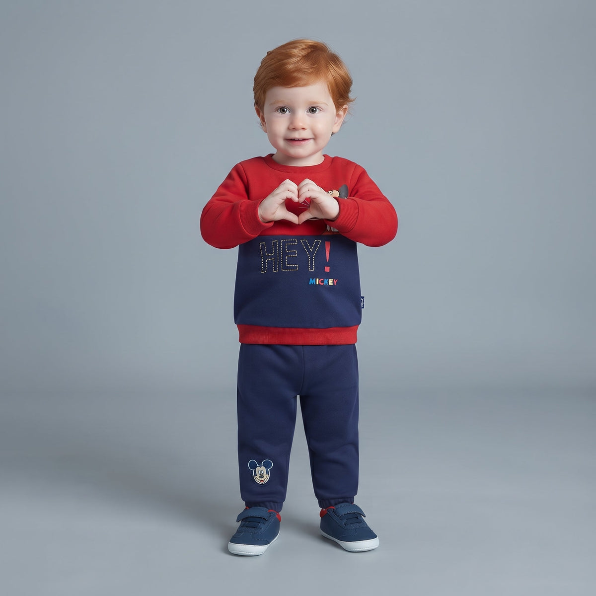 Niño pequeño vistiendo conjunto EmpiBy de Mickey Mouse con sudadera roja y azul y pantalón jogger a juego.