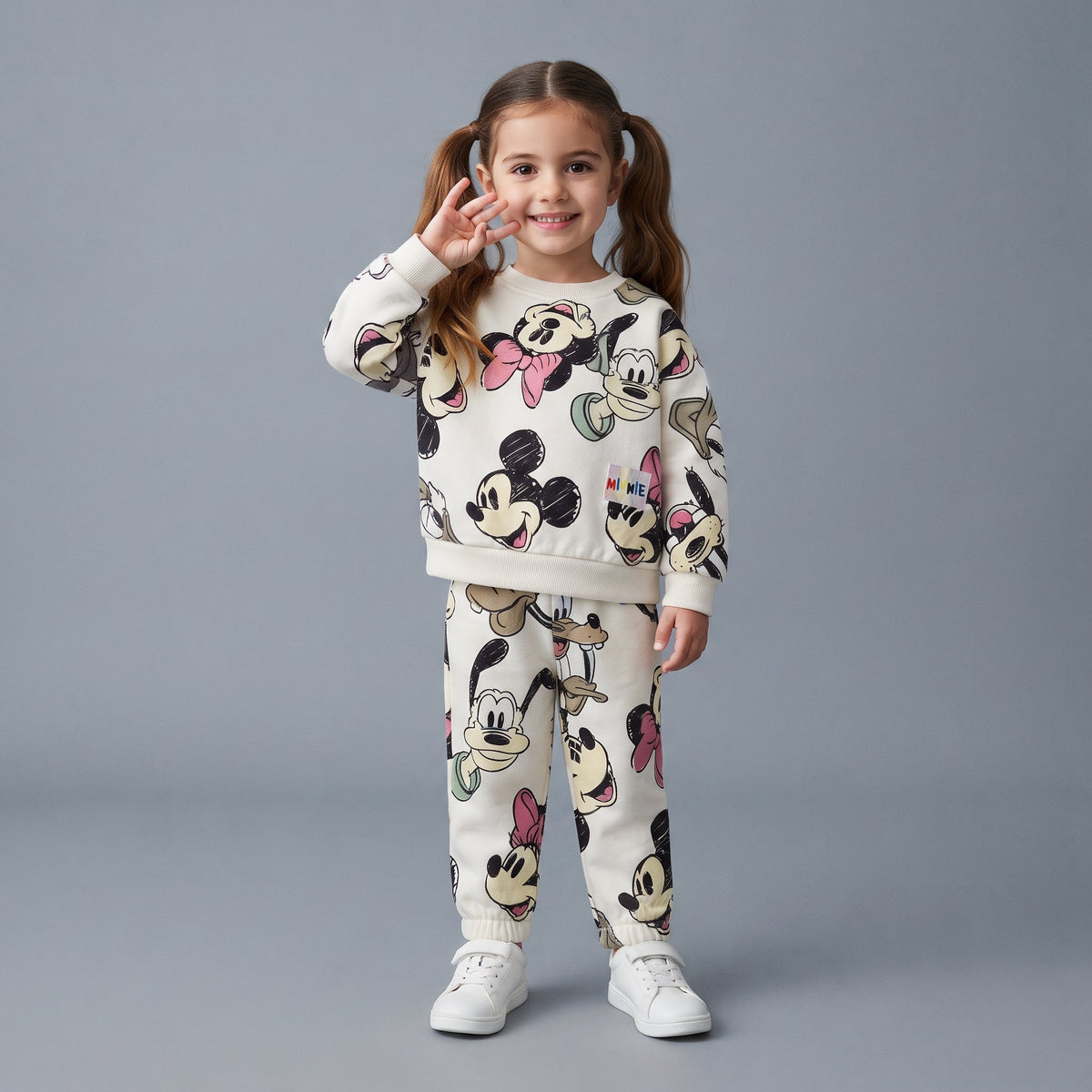 Niña sonriente vistiendo conjunto EmpiBy de dos piezas blanco con estampado de Minnie, Mickey y Pluto