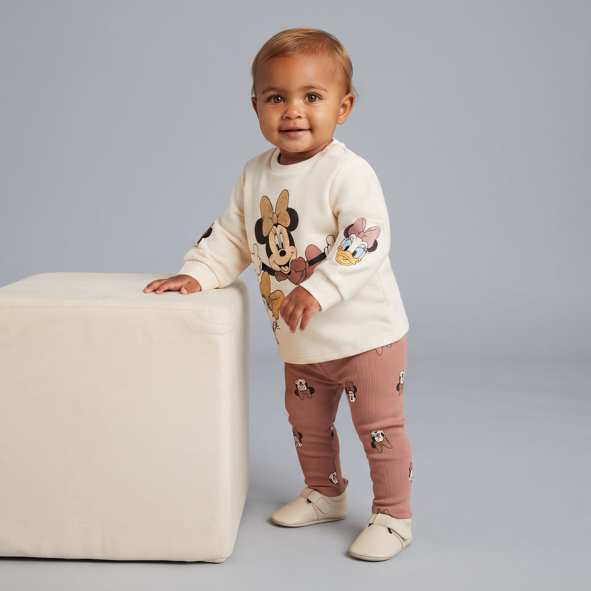 Bebé niña vistiendo conjunto EmpiBy de sudadera marfil con Minnie y Daisy y legging acanalado terracota
