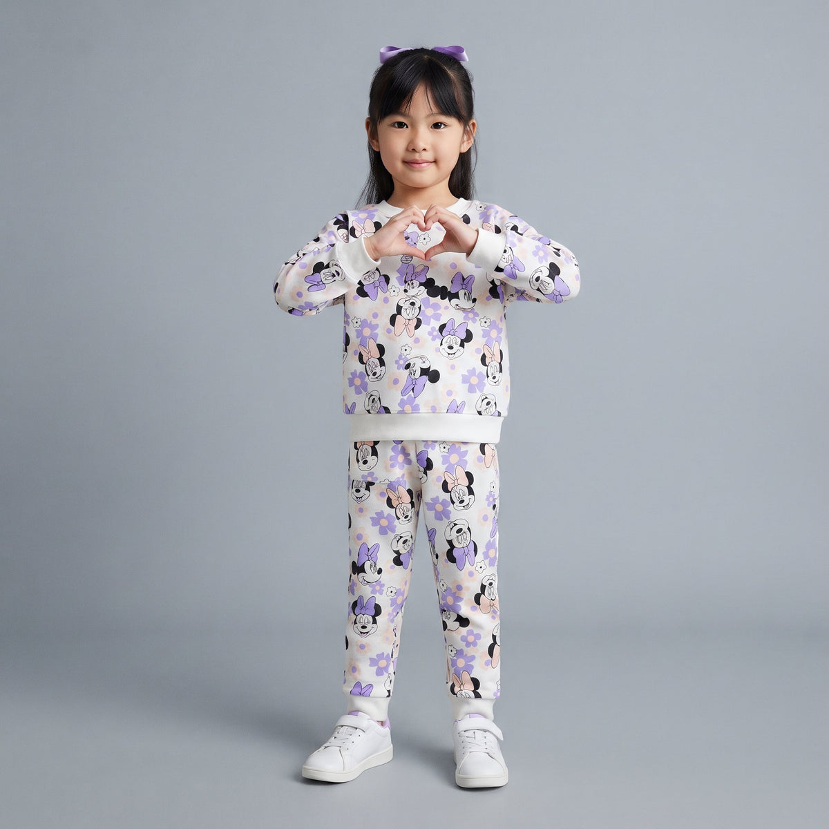 Niña vistiendo conjunto EmpiBy de dos piezas con estampado de Minnie Mouse y flores lilas sobre fondo claro
