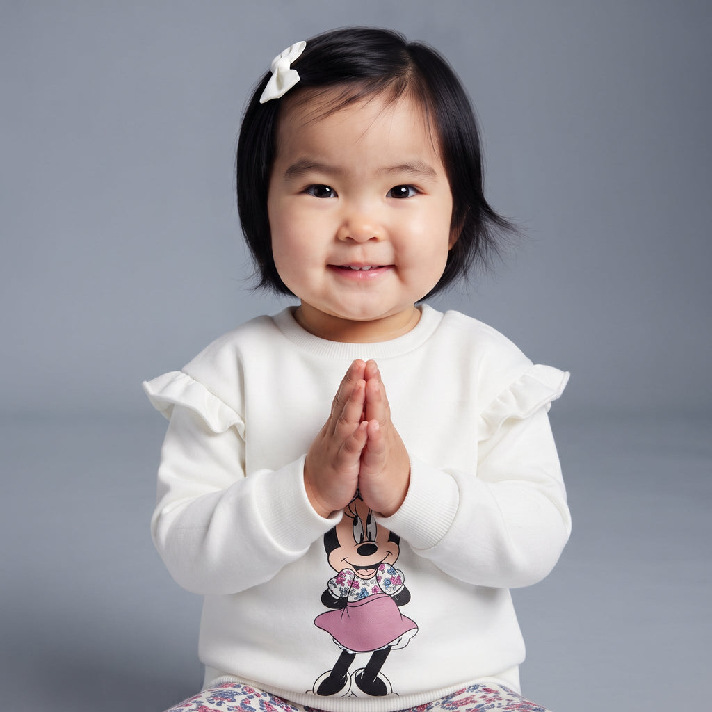 Bebé niña sonriente con conjunto EmpiBy de sudadera blanca con volantes y estampado de Minnie Mouse y legging floral
