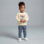 Niña pequeña vistiendo conjunto EmpiBy de sudadera beige con estampado de Minnie Mouse y pantalón azul con flores