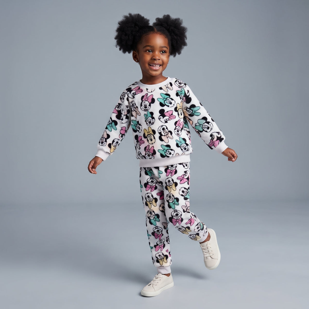 Niña sonriente vistiendo conjunto EmpiBy de dos piezas blanco con estampado colorido de Minnie Mouse y textura suave