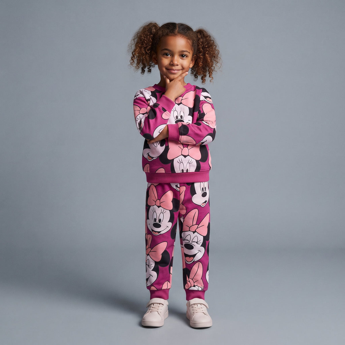 Niña vistiendo conjunto EmpiBy de dos piezas fucsia con estampado integral de Minnie Mouse y lazos rosas