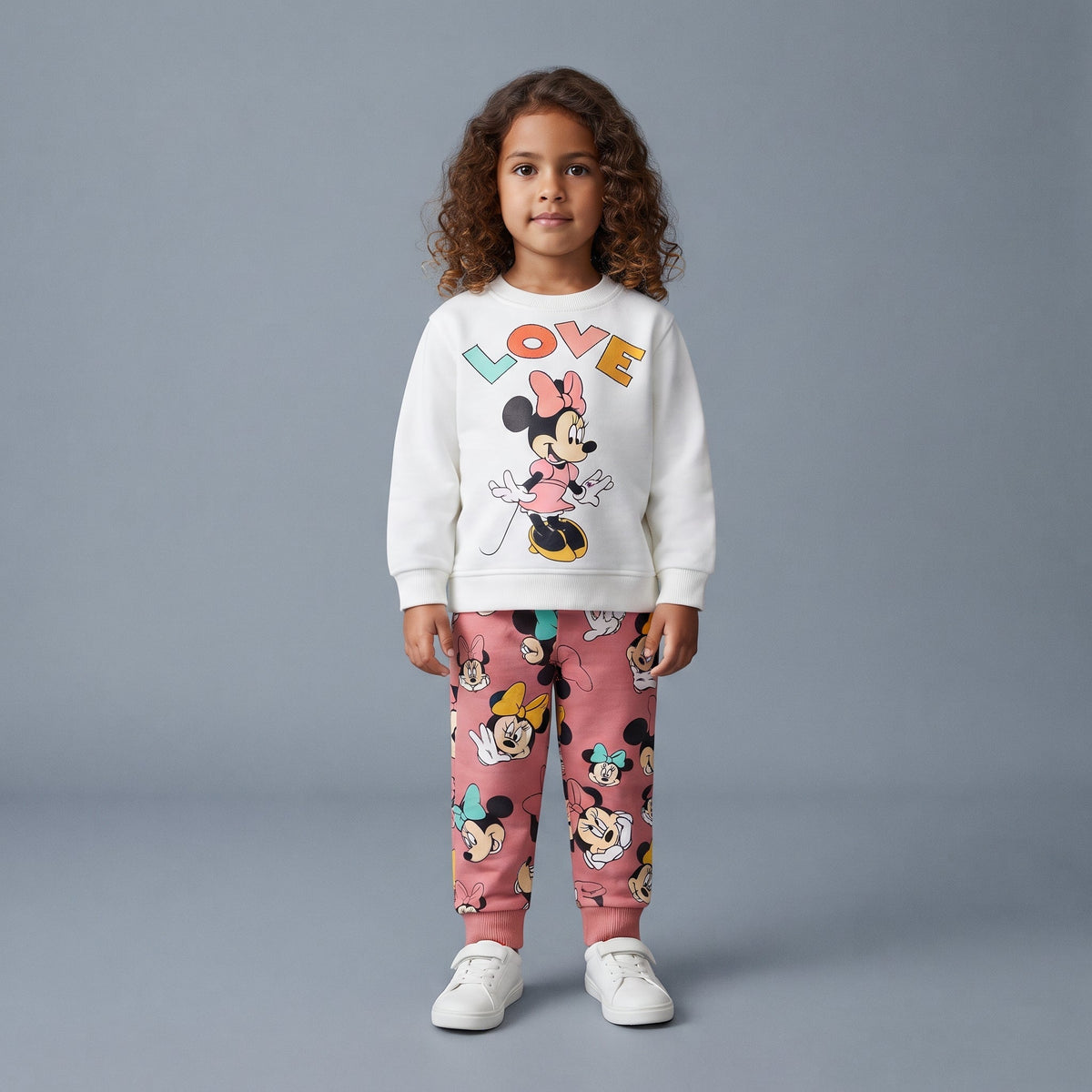 Niña vistiendo conjunto EmpiBy de dos piezas con sudadera blanca Minnie Love y pantalón jogger rosa estampado