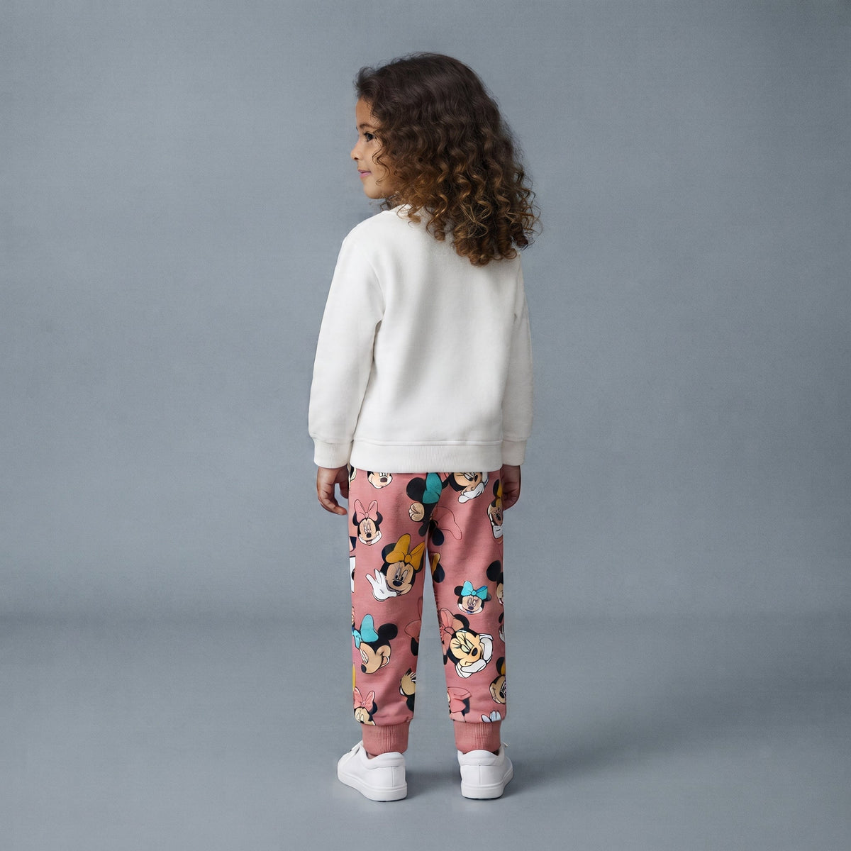 Niña vistiendo conjunto EmpiBy de sudadera blanca y pantalón jogger rosa con estampado de Minnie Mouse y corazones