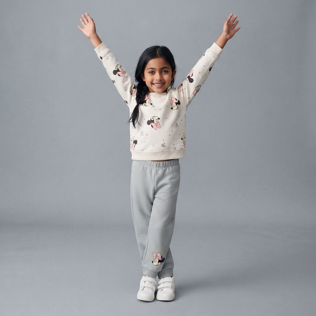 Niña sonriente con conjunto EmpiBy de sudadera blanca estampada de Minnie Mouse y pantalón jogger gris cómodo.