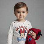 Niña pequeña con conjunto EmpiBy de Minnie Mouse, camiseta blanca de estrellas y chaqueta roja con capucha y lazo.