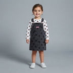 Niña pequeña vistiendo conjunto EmpiBy de peto negro con siluetas de Minnie Mouse y camiseta blanca de manga larga.