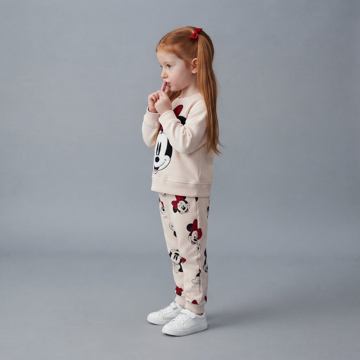 Niña con conjunto EmpiBy de dos piezas de Minnie Mouse en blanco y rojo, sudadera y jogger con estampado clásico.
