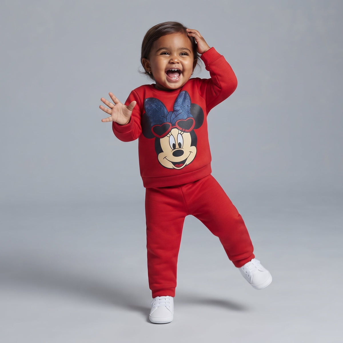 Bebé feliz vistiendo conjunto EmpiBy de dos piezas rojo con estampado de Minnie Mouse y lazo brillante