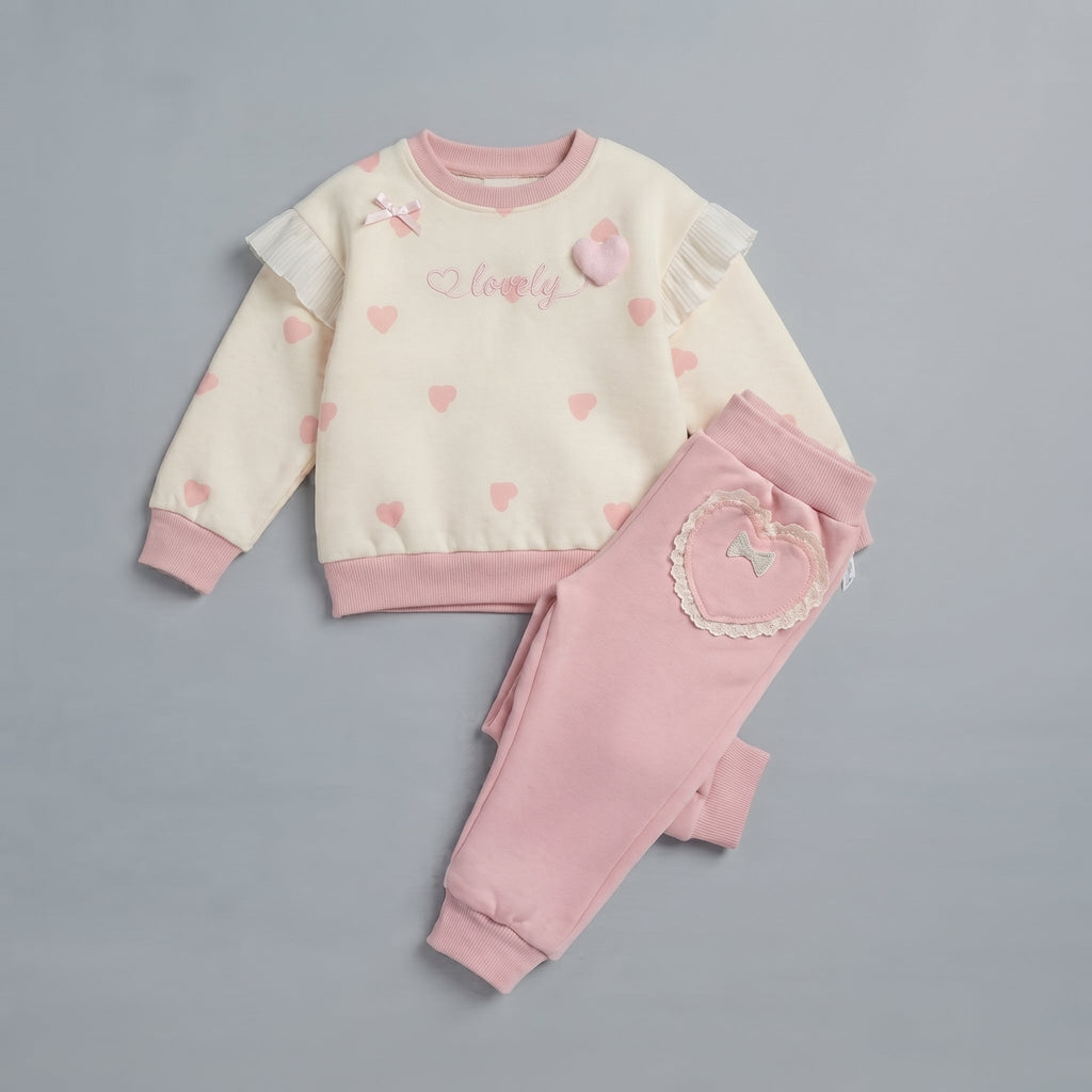 Conjunto EmpiBy de dos piezas para niña con sudadera crema de corazones, encaje y pantalón rosa con bolsillo corazón.