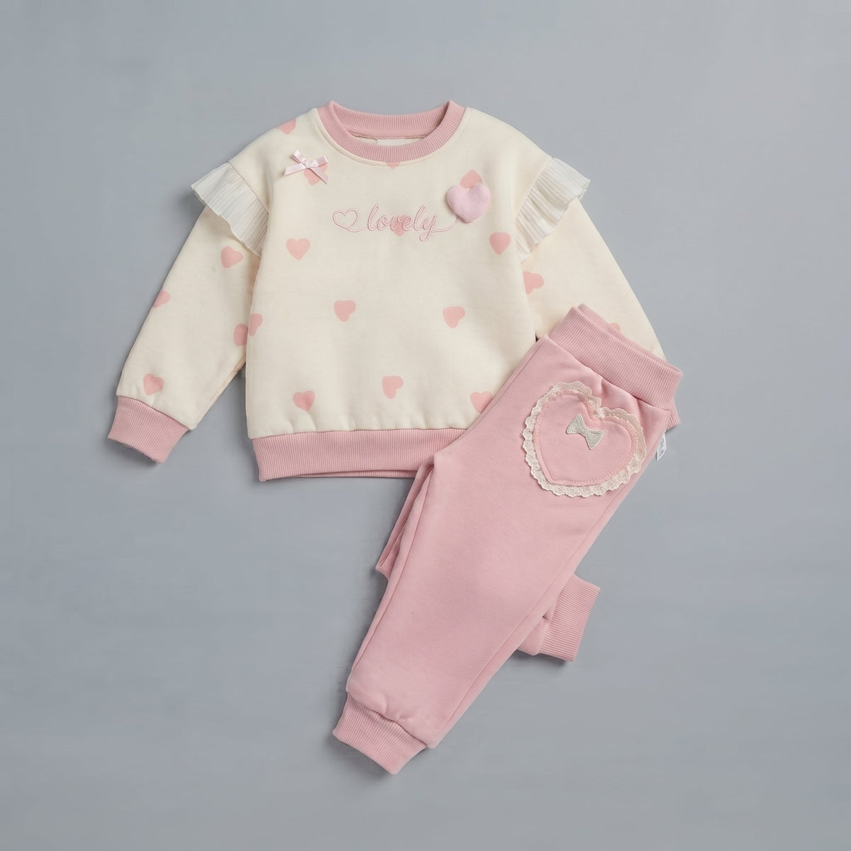 Conjunto EmpiBy de dos piezas para niña con sudadera crema de corazones, encaje y pantalón rosa con bolsillo corazón.