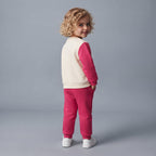 Niña de espaldas vistiendo conjunto EmpiBy de sudadera crema y pantalón jogger fucsia con diseño de Mickey & Friends