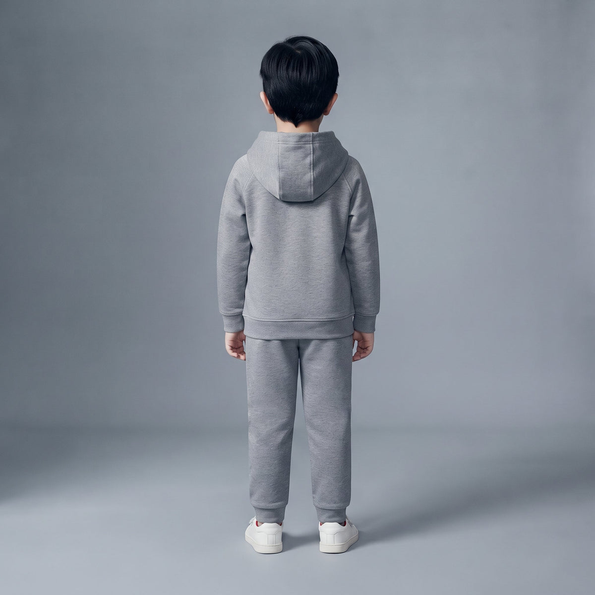 Niño de espaldas vistiendo conjunto EmpiBy de sudadera con capucha y pantalón jogger gris en felpa francesa suave