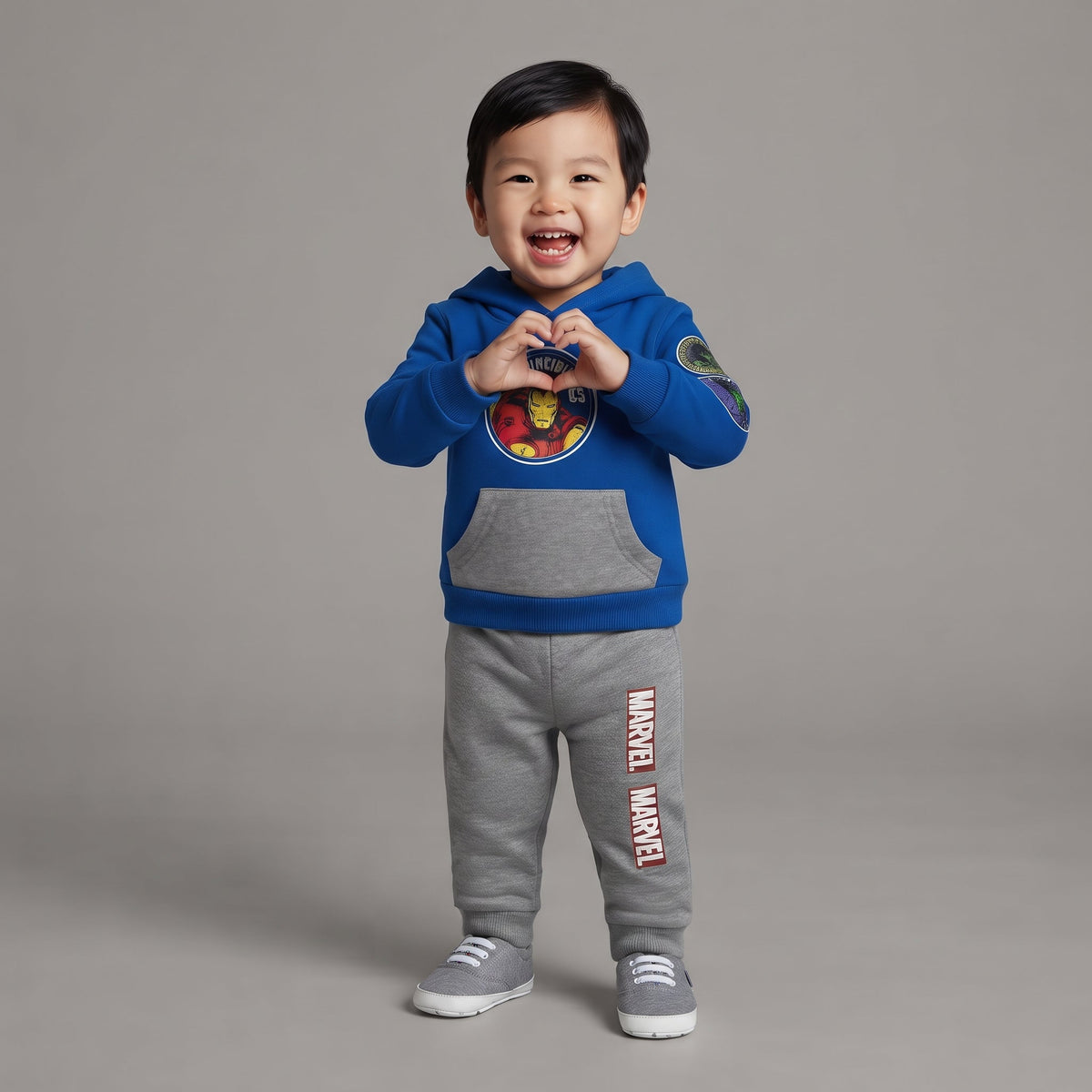 Niño sonriente vistiendo conjunto EmpiBy de Iron Man con sudadera azul, capucha y pantalón jogger gris de Marvel
