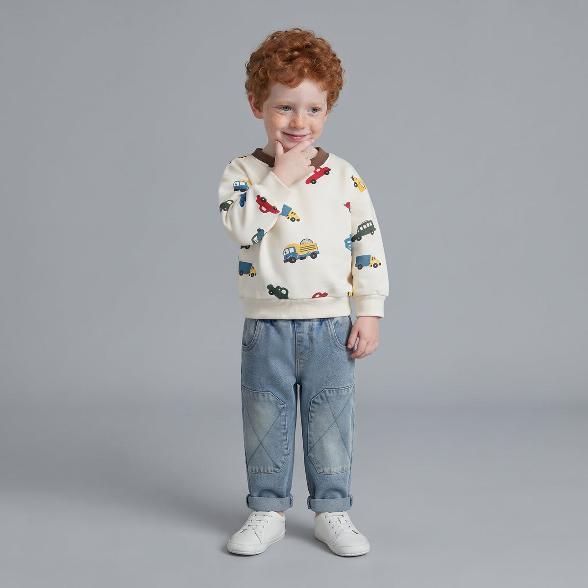 Niño con conjunto EmpiBy de suéter crema estampado de carritos y jeans de mezclilla azul claro con rodillas reforzadas