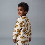 Niño sonriente vistiendo conjunto EmpiBy de dos piezas con estampado de Simba de El Rey León en tonos crema y dorado