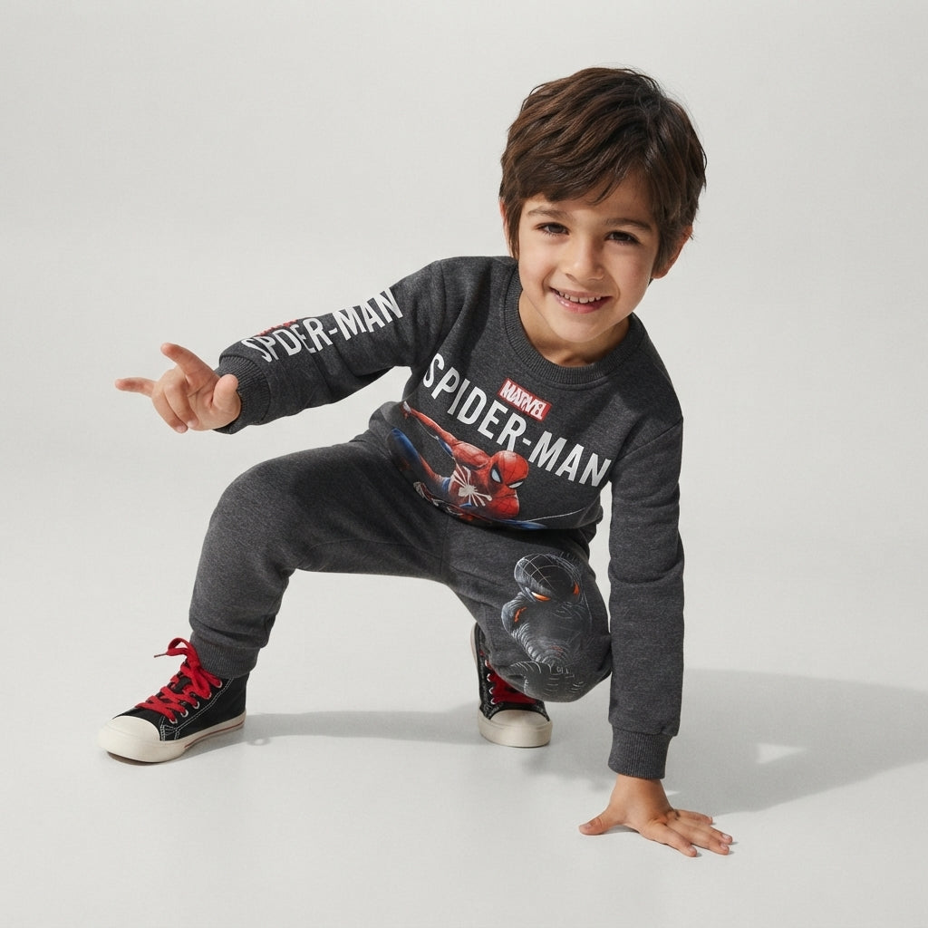 Niño sonriente vistiendo conjunto gris de sudadera y pantalón con estampado de Spider-Man de la marca EmpiBy