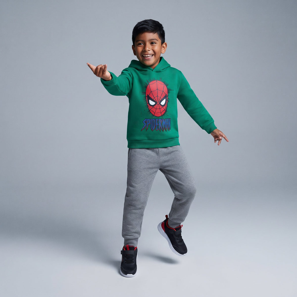 Niño saltando con sudadera verde de Spider-Man y pantalón jogger gris de EmpiBy, estilo casual y cómodo.