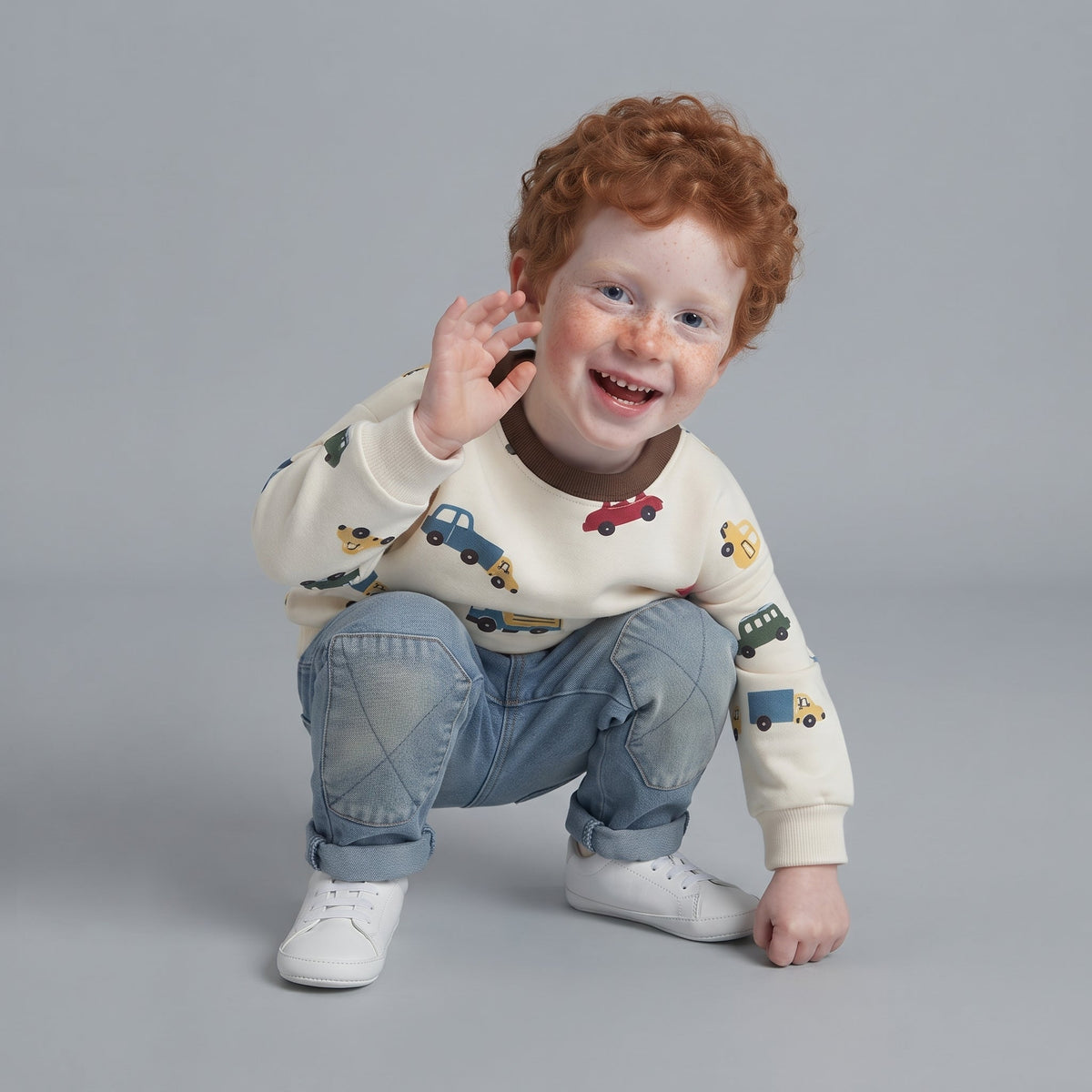 Niño con conjunto EmpiBy de suéter crema estampado de carritos y jeans de mezclilla azul claro con rodillas reforzadas