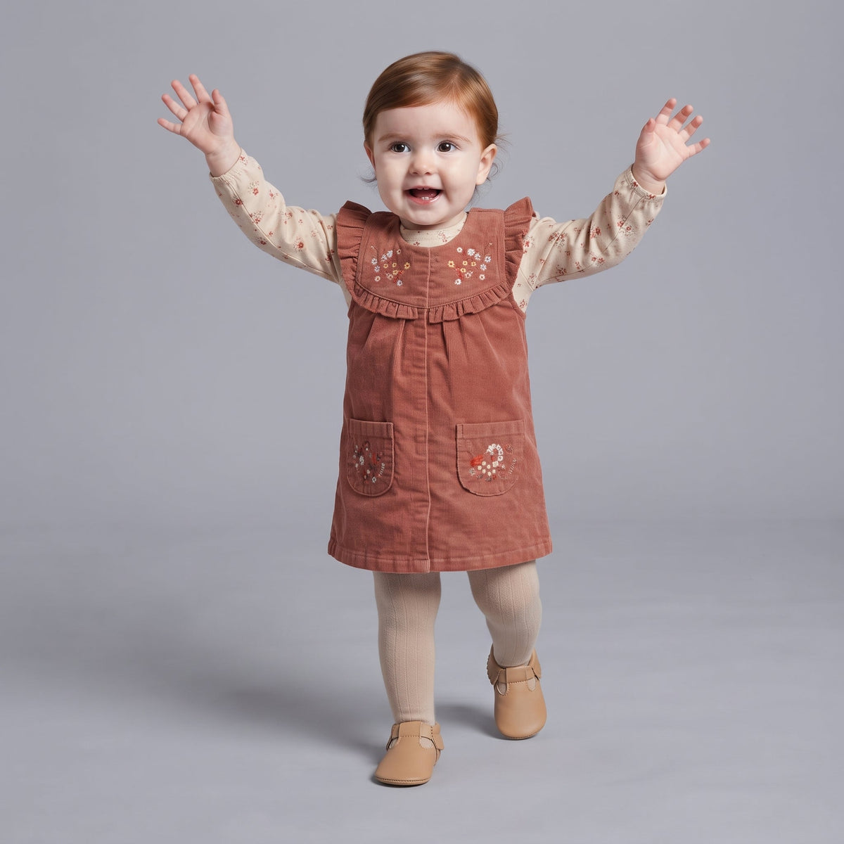 Bebé niña EmpiBy vistiendo un conjunto de pana terracota con bordado floral y camiseta beige de manga larga