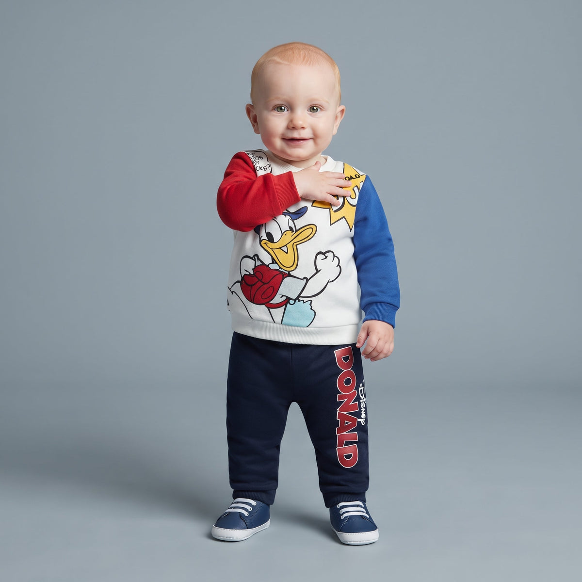 Bebé niño vistiendo conjunto EmpiBy de dos piezas con sudadera del Pato Donald y pantalón jogger azul marino