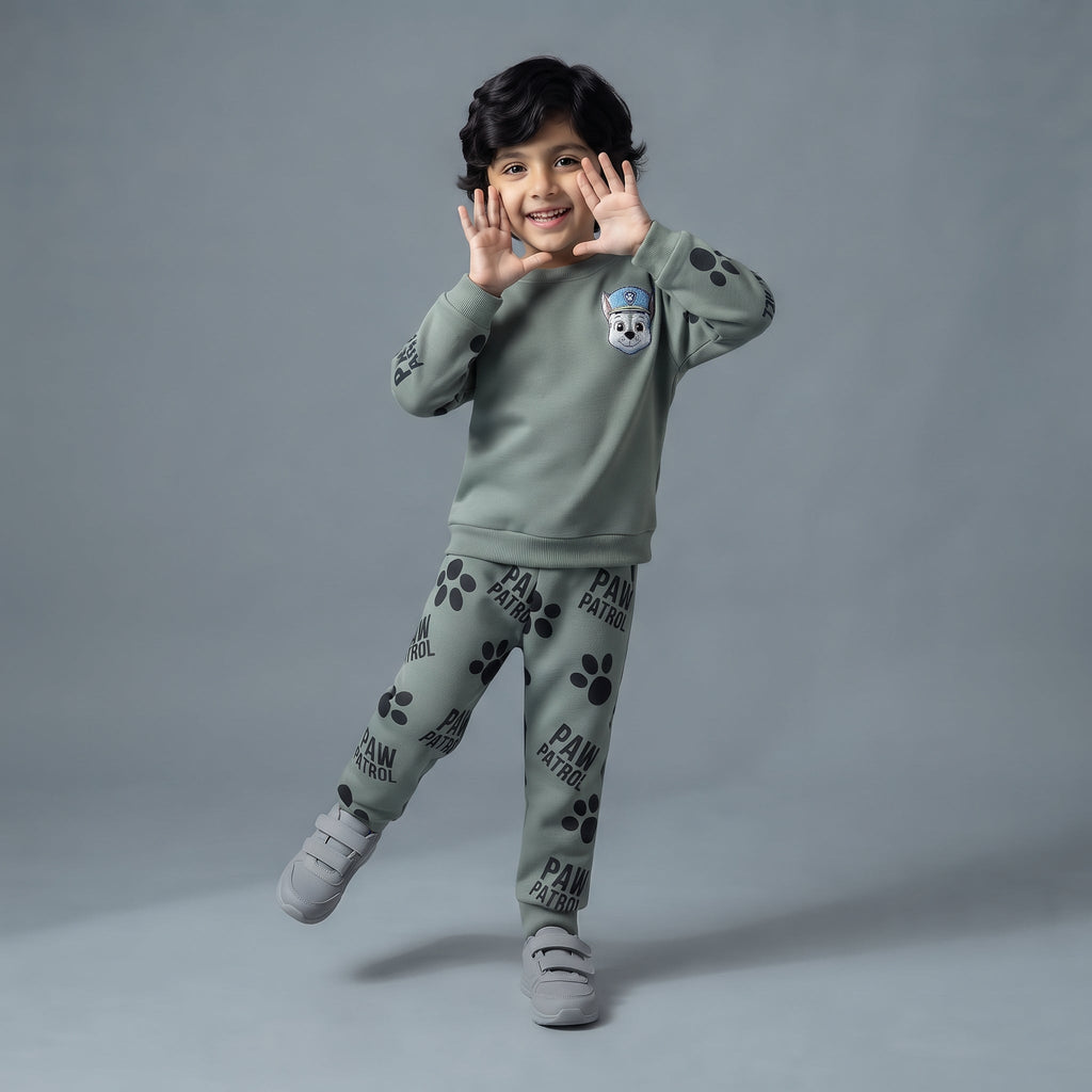 Niño sonriente vistiendo conjunto EmpiBy de Paw Patrol en verde salvia con sudadera de Chase y pantalón de huellas