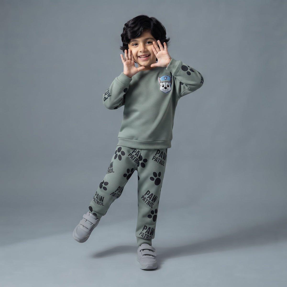 Niño sonriente vistiendo conjunto EmpiBy de Paw Patrol en verde salvia con sudadera de Chase y pantalón de huellas