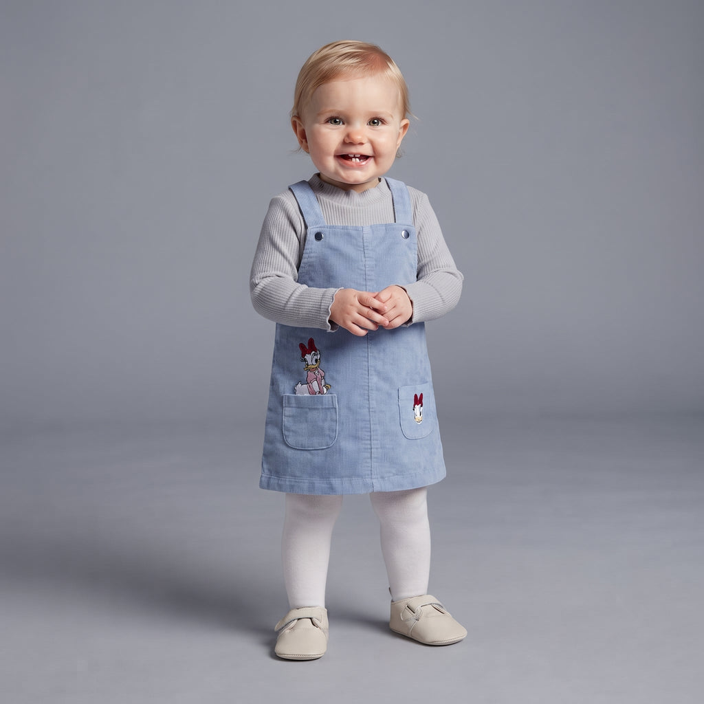 Bebé niña vistiendo conjunto EmpiBy de 3 piezas con vestido de pana azul, camiseta gris y medias blancas de Daisy Duck