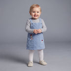 Bebé niña vistiendo conjunto EmpiBy de 3 piezas con vestido de pana azul, camiseta gris y medias blancas de Daisy Duck