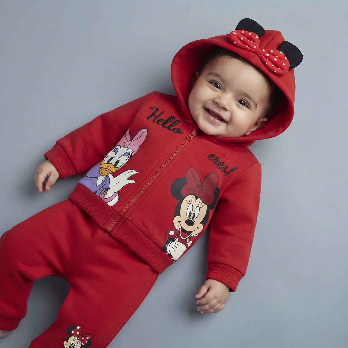 Bebé sonriente con conjunto EmpiBy rojo de Minnie y Daisy, sudadera con capucha, orejas y lazo de lunares.