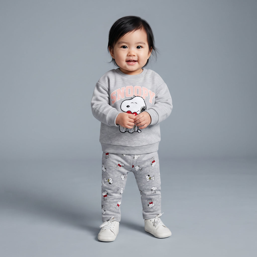 Bebé niña sonriente con conjunto EmpiBy gris de dos piezas con estampado de Snoopy y corazón rojo